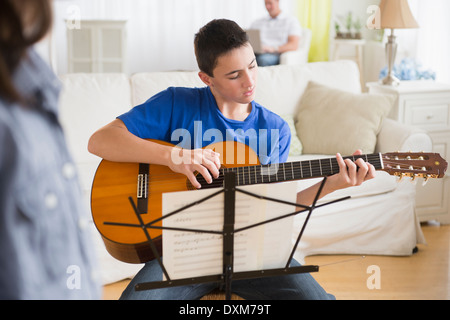 Kaukasische junge Gitarre im Wohnzimmer üben Stockfoto