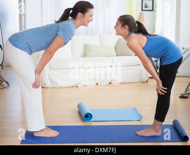 Kaukasische Mutter und Tochter praktizieren Yoga im Wohnzimmer Stockfoto