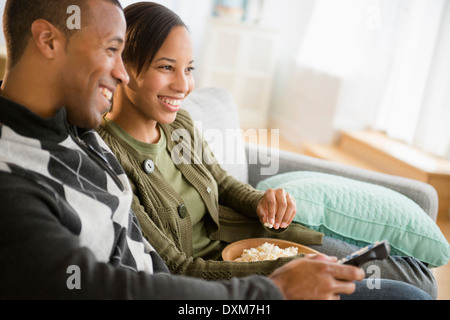 Paar mit Popcorn vor dem Fernseher im Wohnzimmer Stockfoto