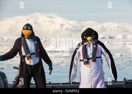 Crew-Mitglieder einer Expedition Kreuzfahrt in die Antarktis in einem Zodiak in Fournier Bucht in die Gerlache Strait auf der antarktischen Halbinsel, als Pinguine verkleidet. Die antarktische Halbinsel ist eines der am schnellsten Erwärmung Gebiete auf dem Planeten. Stockfoto