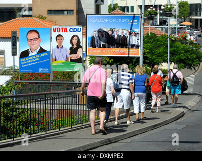 Madeira Portugal. Camara de Lobos. Touristen zu Fuß vorbei an lokalen Wahlen Werbung Schilder Stockfoto