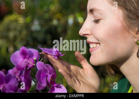 Frau riecht um schöne Orchidee Blume Stockfoto