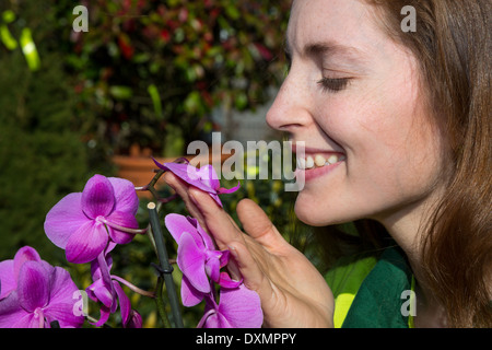 Frau riecht um schöne Orchidee Blume Stockfoto