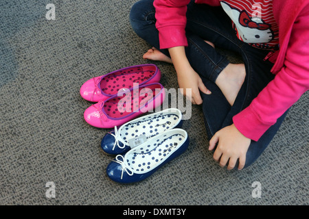 Kingston Upon Thames Surrey John Lewis Store Mädchen sitzen auf Boden Auswahl Schuhe rosa Ballett Pumpe und blau Stockfoto