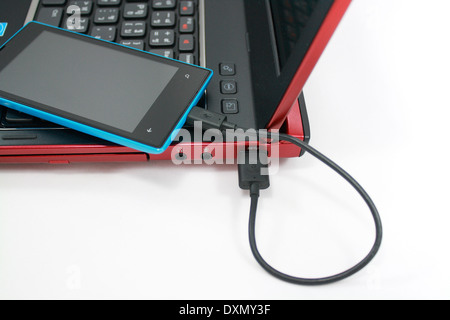 eine Smartphone ist an einen Laptop anschließen und Ladeleistung von ihm Stockfoto