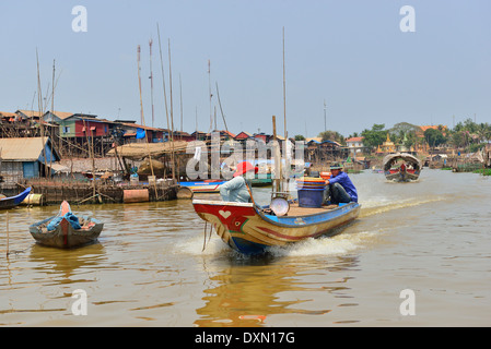 "Long-Tail" Schnellboot, das entlang Fluss mit Häusern auf Stelzen am Ufer des Tonle SAP Lake, Kambodscha, Südostasien produziert Stockfoto