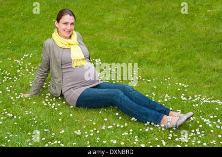 Schöne schwangere Frau Entspannung im Park auf dem grünen Rasen Stockfoto