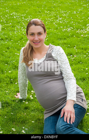 Schöne schwangere Frau Entspannung im Park auf dem grünen Rasen Stockfoto