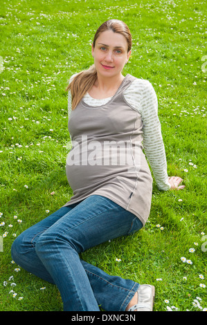 Schöne schwangere Frau Entspannung im Park auf dem grünen Rasen Stockfoto