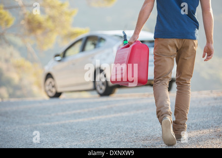 Mann mit Gas kann zu Auto am Straßenrand Stockfoto