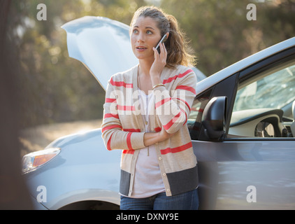 Frau am Handy mit Kfz Motorhaube angehoben am Straßenrand Stockfoto