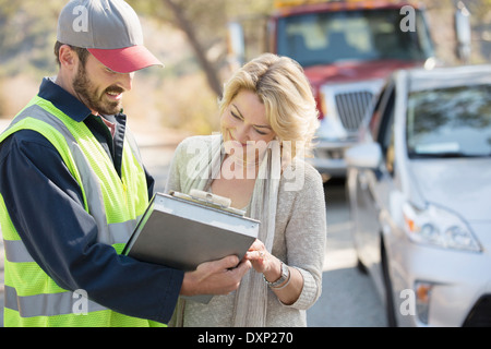 Am Straßenrand Mechaniker und Frau Überprüfung Papierkram Stockfoto