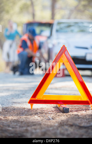 Am Straßenrand Mechaniker helfen Frau hinter Warndreieck Stockfoto