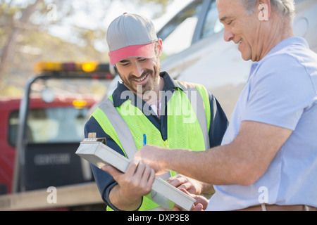 Mann, die Unterzeichnung Papierkram am Straßenrand Mechaniker Stockfoto