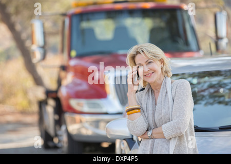 Frau am Handy in der Nähe von Abschleppwagen am Straßenrand Stockfoto