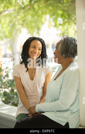 Mutter und Tochter sprechen auf Veranda Stockfoto