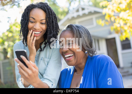 Mutter und Tochter Blick auf Handy und lachen Stockfoto