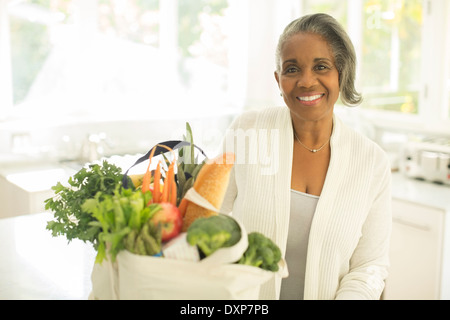 Portrait von lächelnden senior Frau mit Lebensmittel in der Küche Stockfoto