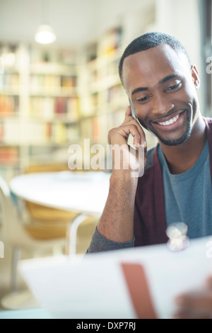 Lächelnd Mann mit Papierkram reden über Handy