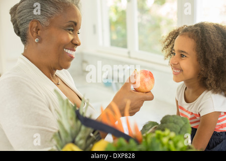 Glückliche Großmutter Enkelin in Küche und Apple verleiht Stockfoto