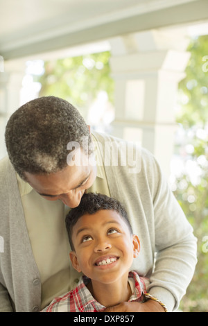 Großvater umarmt Enkel auf Veranda Stockfoto