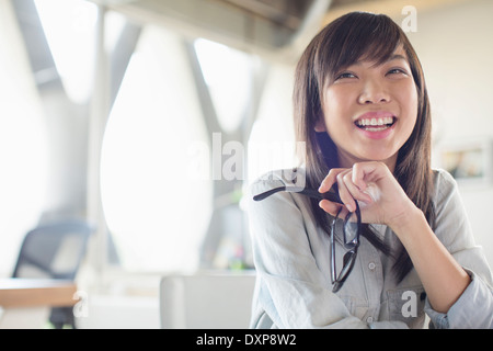 Geschäftsfrau hält Brillen und Lachen im Büro Stockfoto