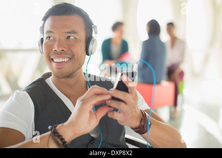 Lässige Geschäftsmann anhören von Musik über Kopfhörer mit MP3-player