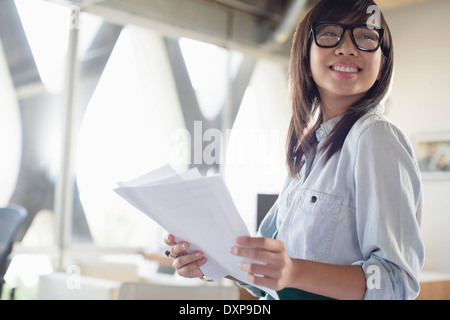 Glücklich kreative Geschäftsfrau mit Papierkram im Büro Stockfoto