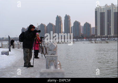 Fotografen, die Bilder von der untergehenden Sonne über dem Fluss Songhua-Fluss im Winter. Provinz Jilin City, Jilin Stockfoto