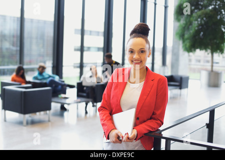 Hübsche junge Frau mit einem Laptop stehen durch ein Geländer, Blick auf die Kamera zu Lächeln. Jungen afroamerikanischen Geschäftsfrau. Stockfoto