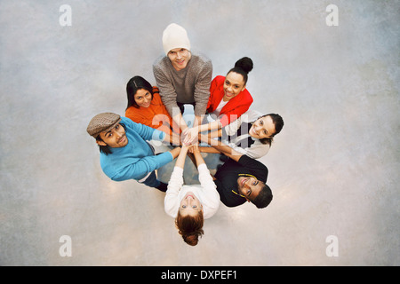 Gruppe von glücklichen jungen Studenten zeigen. Draufsicht der multiethnische Gruppe junger Leute setzen ihre Hände zusammen. Stockfoto