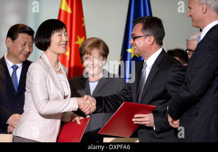 In Anwesenheit des chinesischen Präsidenten Xi Jinping (L) und Bundeskanzlerin Angela Merkel (C) unterzeichnen Hu Xiaolan, stellvertretender Gouverneur (für die Peoples Bank of China) und Vorstandsmitglieder der Deutschen Bundesbank, Joachim Nagel und Carl-Ludwig Thiele (R), eine Absichtserklärung für den Finanzplatz Frankfurt/Main in der Kanzlei in Berlin, Deutschland, 28. März 2014. China und Deutschland wollen ein Handelszentrum für die chinesische Währung Yuan in das deutsche Finanzkapital zu bauen. Es ist der erste Staatsbesuch des chinesischen Präsidenten nach Deutschland in acht Jahren. Foto: SOEREN STACHE/dpa Stockfoto