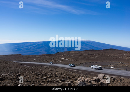 Autos auf Mauna Kea Gipfel Straße. Mauna Loa im Hintergrund. Big Island von Hawaii. Stockfoto