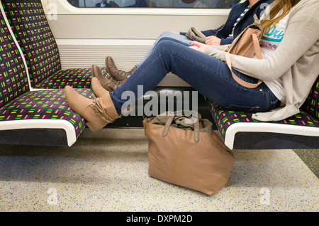 Junge Frau mit Füße auf die Sitze auf die Londoner U-Bahn, Großbritannien Stockfoto