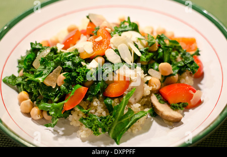 Gesundes, pflanzenbasiertes Abendessen mit Quinoa mit Grünkohl, Kichererbsen, Pilzen, Paprika und Mandelscheiben. Glutenfrei und vegan. Stockfoto