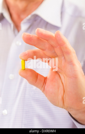 Älterer Erwachsene Mann Medizin Kapsel hält in seiner Hand und zeigt auf Kamera hautnah. Stockfoto