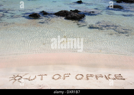 Aus dem Amt geschrieben am Sand an einem wunderschönen Strand blaue Wellen im Hintergrund Stockfoto