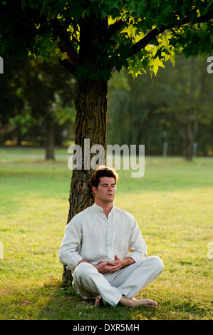 Junger Mann unter einem Baum zu meditieren Stockfoto