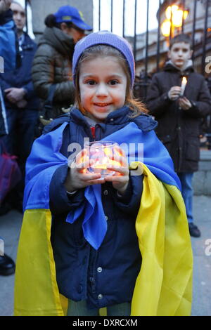 Dublin, Irland. 29. März 2014. Ein kleines Mädchen abgebildet ist, in einem ukrainischen Flagge gehüllt und mit einer brennenden Kerze. Ukrainer und Iren sowie Anhänger aus anderen Ländern versammelten Dail (Irisches Parlament) in Unterstützung mit den Menschen und Demokratie in der Ukraine und gegen die Besetzung der autonomen Republik der Krim durch Russland. Bildnachweis: Michael Debets/Alamy Live-Nachrichten Stockfoto