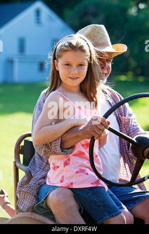 Junges Mädchen mit Großvater einen Traktor zu fahren, auf einem Bauernhof Stockfoto