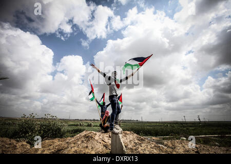 Gaza, Palästinensische Gebiete. 30. März 2014. Ein Demonstrant "Wellenlinien" eine palästinensische Fahne in Richtung der israelischen Grenze während einer Protestaktion anlässlich Tag des Bodens an der Grenze zwischen Israel und Gaza-Streifen am 30. März 2014. 30 März markiert Tag des Bodens, die jährliche Gedenkfeier der Proteste im Jahr 1976 gegen Israels Aneignung von arabischen besaß Land in Galiläa. Bildnachweis: Momen Faiz/NurPhoto/ZUMAPRESS.com/Alamy Live-Nachrichten Stockfoto