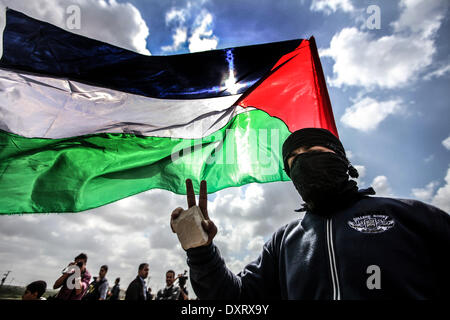 Gaza, Palästinensische Gebiete. 30. März 2014. Ein Demonstrant "Wellenlinien" eine palästinensische Fahne in Richtung der israelischen Grenze während einer Protestaktion anlässlich Tag des Bodens an der Grenze zwischen Israel und Gaza-Streifen am 30. März 2014. 30 März markiert Tag des Bodens, die jährliche Gedenkfeier der Proteste im Jahr 1976 gegen Israels Aneignung von arabischen besaß Land in Galiläa. Bildnachweis: Momen Faiz/NurPhoto/ZUMAPRESS.com/Alamy Live-Nachrichten Stockfoto