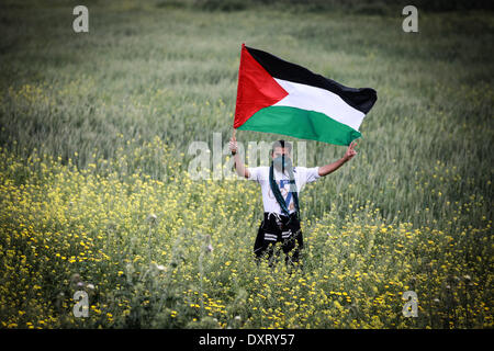 Gaza, Palästinensische Gebiete. 30. März 2014. Ein Demonstrant "Wellenlinien" eine palästinensische Fahne in Richtung der israelischen Grenze während einer Protestaktion anlässlich Tag des Bodens an der Grenze zwischen Israel und dem Gazastreifen 30. März 2014. 30 März markiert Tag des Bodens, die jährliche Gedenkfeier der Proteste im Jahr 1976 gegen Israels Aneignung von arabischen besaß Land in Galiläa. Bildnachweis: Majdi Fathi/NurPhoto/ZUMAPRESS.com/Alamy Live-Nachrichten Stockfoto