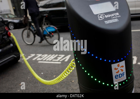 Radfahrer geht eine elektrische Leistung von geparkten Smart Auto lädt ein EEF Ladestation im Zentrum von London. Stockfoto