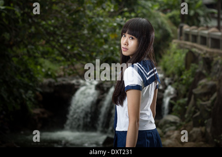 Niedlichen chinesischen Schulmädchen mit Wasserfall im Hintergrund Stockfoto