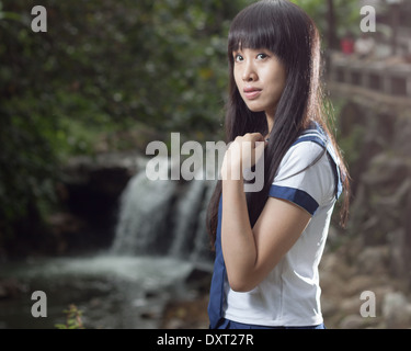 Niedlichen chinesischen Schulmädchen mit Wasserfall im Hintergrund Stockfoto