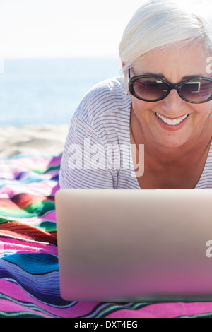 Glückliche Frau mit Laptop am Strand Stockfoto