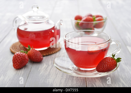 Erdbeertee in Glasschale mit Teekanne und frischen Beeren auf hölzernen Hintergrund Stockfoto