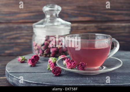 Teerose Blumen in Glas und Tee auf hölzernen Hintergrund Stockfoto