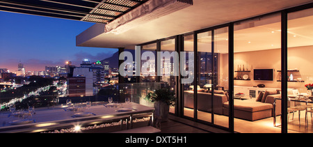 Beleuchtete moderne Wohnzimmer und Terrasse mit Blick auf die Stadt Stockfoto